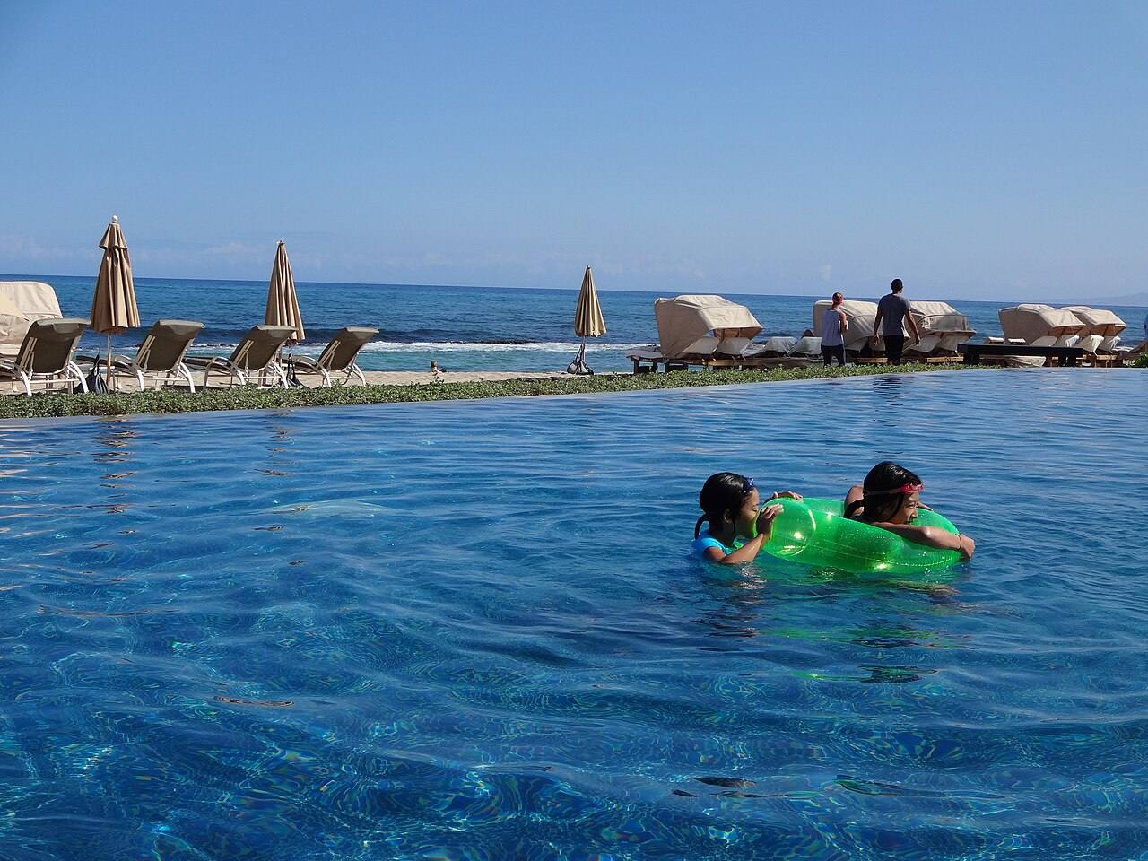 Piscina de borda infinita junto ao mar, com espreguiçadeiras