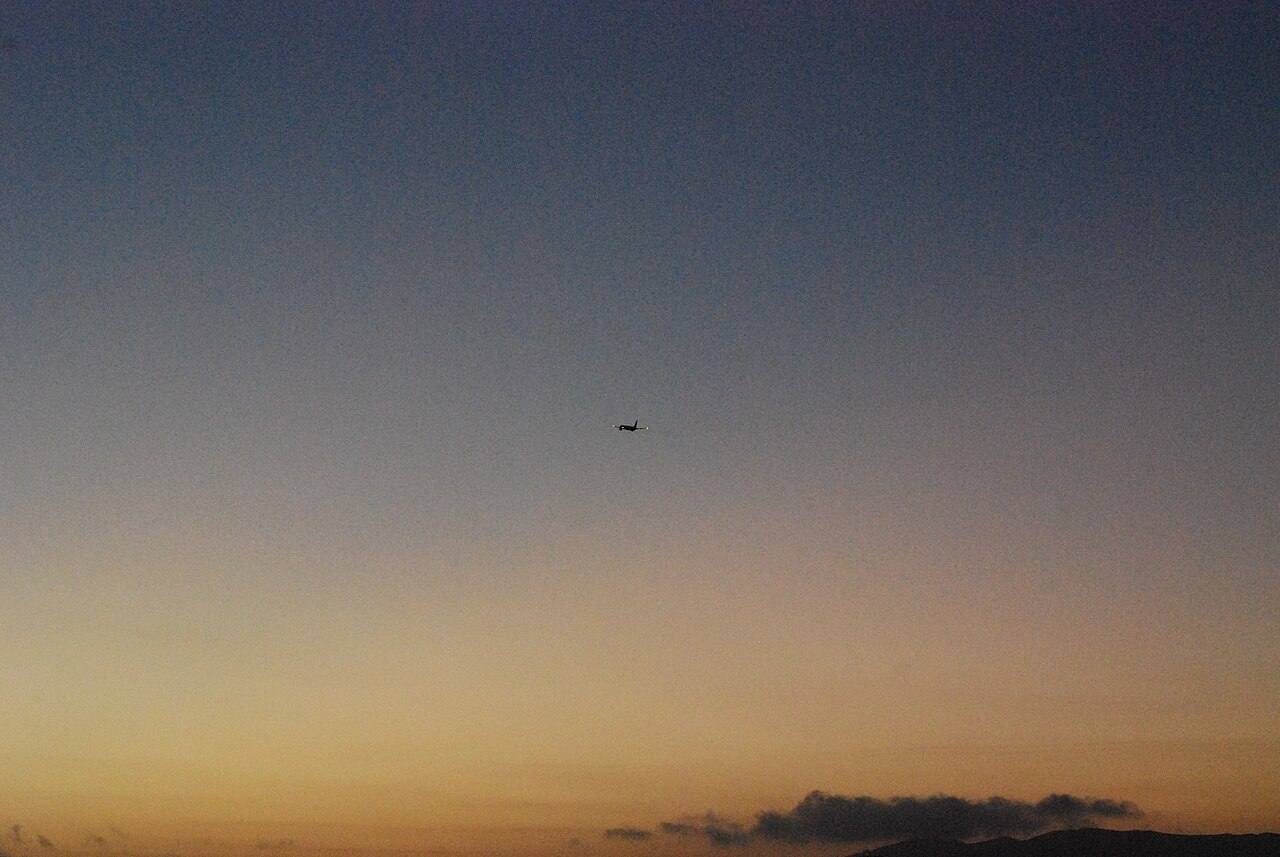 Avião a subir contra o céu depois do pôr do sol